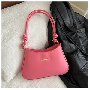 Détail d'un sac porté épaule en cuir rose vif avec fermoir doré sur fond blanc