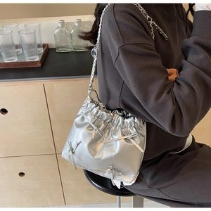 Vue détaillée du sac seau métallisé argenté avec plis, nœuds et bandoulière chaîne