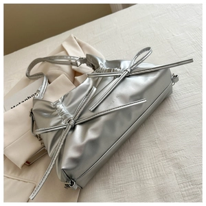 Detailed close-up of metallic silver tote bag featuring pleated bows and chic glossy texture