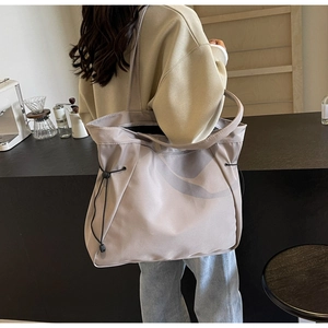 Detail of the large tote bag showing side drawstring and smooth nylon texture