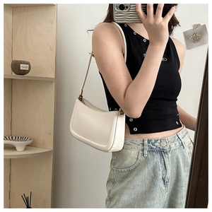 Mirror selfie showing a woman wearing a minimalist white leather crescent shoulder bag