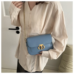 Détail d'un petit sac bleu clair avec boucle dorée CD porté par un mannequin