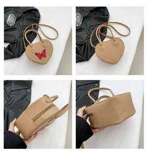 Detail view of heart-shaped beige handbag showing zippers, handles and spacious interior