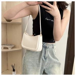 Minimalist white semi-circle underarm bag shown as worn with a stylish shoulder strap