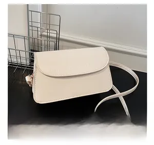Detailed shot of cream white crocodile embossed texture on a chic faux leather crossbody bag