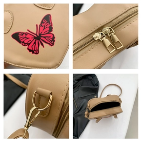 Detail view of khaki heart-shaped bag showing butterfly print and dual metal zippers