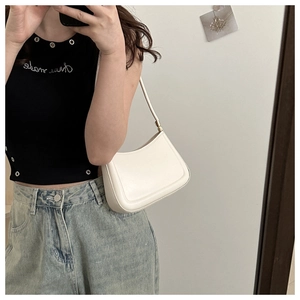 White minimalist leather baguette bag shown as a shoulder carry with a casual outfit