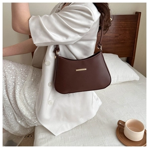 Detail of elegant dark brown faux leather shoulder bag with minimalist gold metal bar