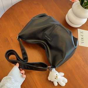 Minimalist black matte tote bag with teddy charm on a wooden table with Vogue cards
