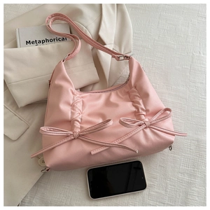 Detailed view of pink pleated bow bag next to smartphone showing practical capacity