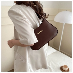 Détail du sac sous le bras en similicuir marron foncé avec garniture en métal doré