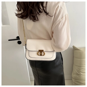 Détail d'un sac bandoulière crème chic avec boucle CD dorée et bandoulière chaîne en métal