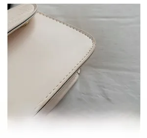 Macro shot of precise stitching and fine leather texture on the beige shoulder bag