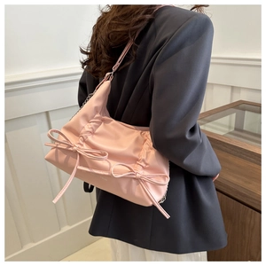 Detail of pink pleated underarm bag with bow decoration and silver metal chain strap