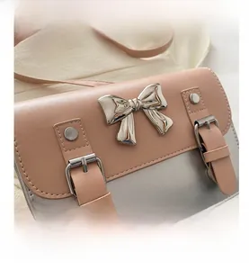 Detail of silver metallic bow and leather buckle on pink two-tone satchel bag