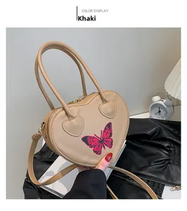 Detail of khaki heart-shaped handbag with red butterfly print and dual handles
