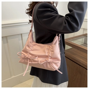 Detail of pink pleated tote bag with double bow decoration and metal chain strap
