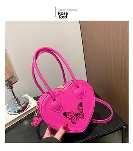 Detail of rose red heart-shaped handbag featuring butterfly print and gold hardware