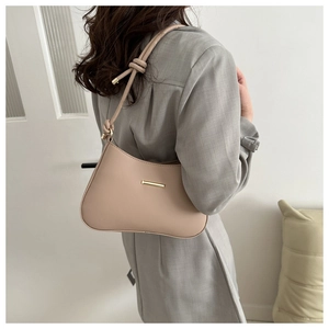 Dettaglio borsa sottospalla beige con tracolla a nodo e inserti in metallo oro