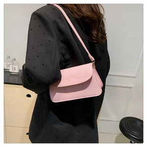 Pink shoulder bag detail showing crocodile texture and gold hardware on model
