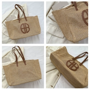 Detail of woven straw tote bag with brown leather handles and decorative round logo