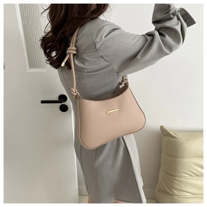 Detail of apricot crescent shoulder bag featuring gold hardware and a knotted strap