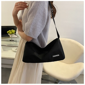 Close-up of lightweight black nylon crossbody bag with fashion label and adjustable strap