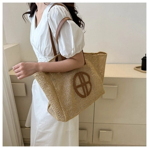 Close-up of woven straw tote bag featuring detailed texture and brown leather handles