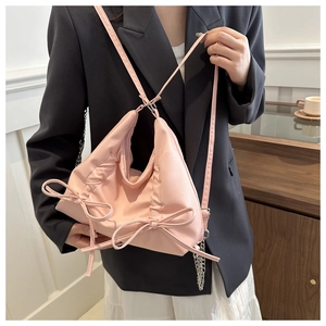 Detail of pink pleated bow tote with metal chain and adjustable shoulder strap