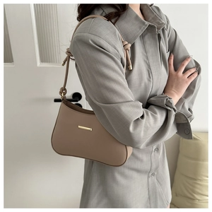 Detail of beige PU leather shoulder bag with gold metal trim and knotted strap detail