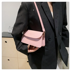 Detail view of pink stone textured shoulder bag worn with a black rivet blazer