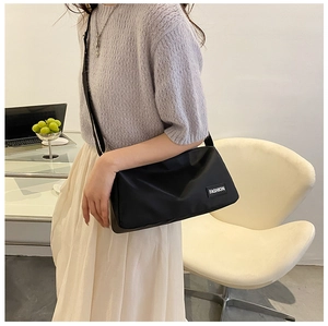 Close-up of lightweight black nylon crossbody bag with a fashion label on casual model