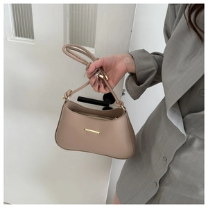 Détail du sac sous le bras en cuir beige avec garniture dorée et bandoulière à nœuds