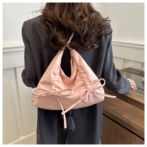 Detailed side view of a pink soft leather hobo bag with cute bow ties and ruched design