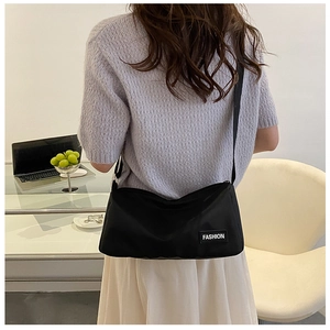 Lifestyle view of black nylon crossbody bag with adjustable strap and fashion label detail