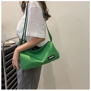 Detail view of a bright green nylon crossbody bag showing the fashion label and texture