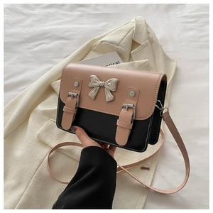 Close-up of pink and black square bag featuring a silver metal bow and fine stitching