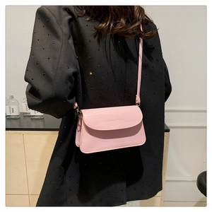 Detailed view of pink crocodile pattern flap bag with slim strap on black blazer