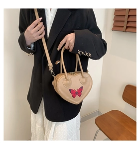 Close-up of heart-shaped handbag with butterfly print and adjustable shoulder strap
