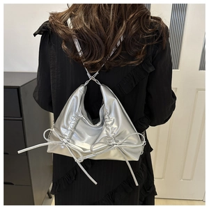 Silver metallic pleated shoulder bag featuring large bows on a black dress model