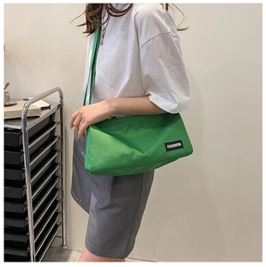 Close-up of bright green nylon crossbody bag featuring fashion label and shoulder strap