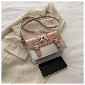 Detail of pink and silver color-block crossbody bag with metallic bow and buckle accents