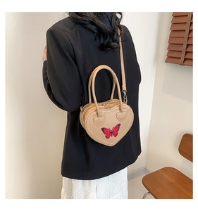 Beige heart-shaped bag with red butterfly embroidery shown as a stylish crossbody detail