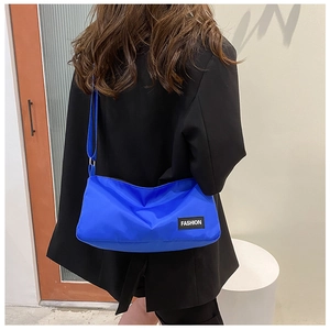 Blue oxford fabric crossbody bag shown on model highlighting nylon texture and fashion tag