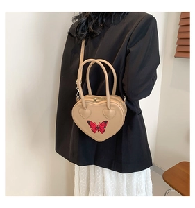 Detail of heart-shaped handbag with red butterfly embroidery and khaki leather texture