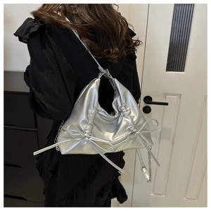 Detail of silver ruched tote bag with side bows and leather metal chain strap