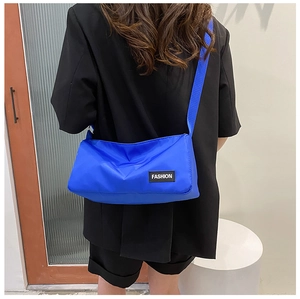 Rear view of model wearing a blue nylon crossbody bag with adjustable strap and fashion label