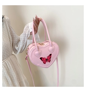 Detail of pink heart-shaped leather handbag with butterfly embroidery and gold hardware