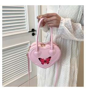 Detail of pink heart-shaped handbag with butterfly embroidery and golden zipper