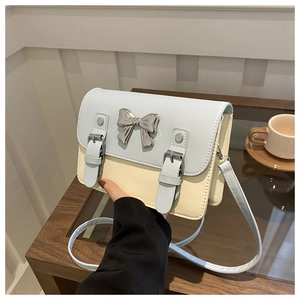 Detail of color-block satchel with metal bow and buckle on a wooden cafe table